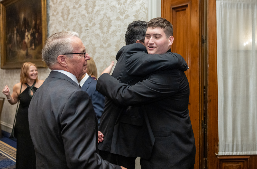 John Pryor, Jr. hugs a former colleague of his father’s, as Schwab watches.